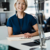 Professional woman smiling at her desk. A smiling professional woman sitting at her office desk.